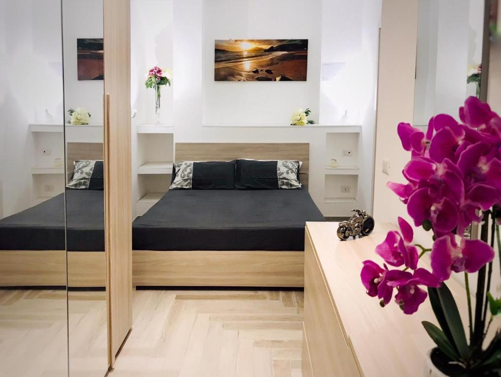 1 Schlafzimmer mit 2 Betten, einem Spiegel und lila Blumen in der Unterkunft appartamento per mare o centro storico di Roma in Lido di Ostia