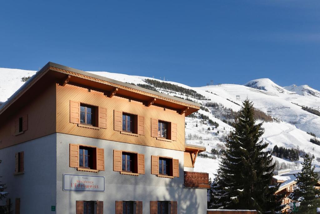 a building in front of a snow covered mountain at Vacancéole - Résidence L'Edelweiss in Les Deux Alpes