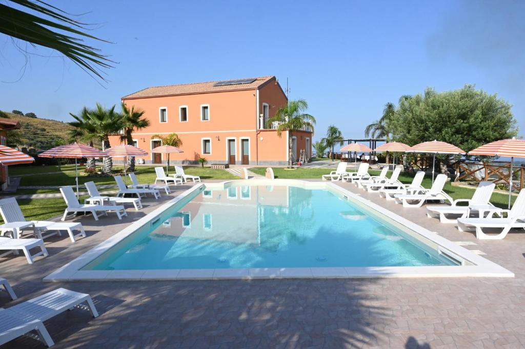 a swimming pool with chairs and umbrellas in front of a building at Arcobaleno dell'Etna in Calatabiano