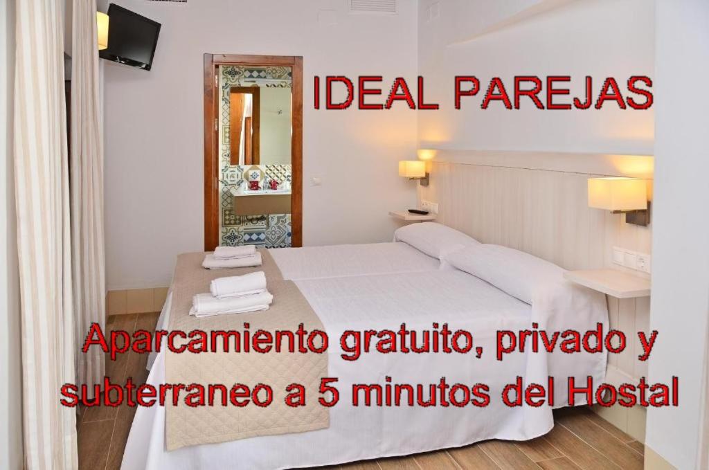 een slaapkamer met een wit bed en een spiegel bij Hostal La Fonda in Conil de la Frontera