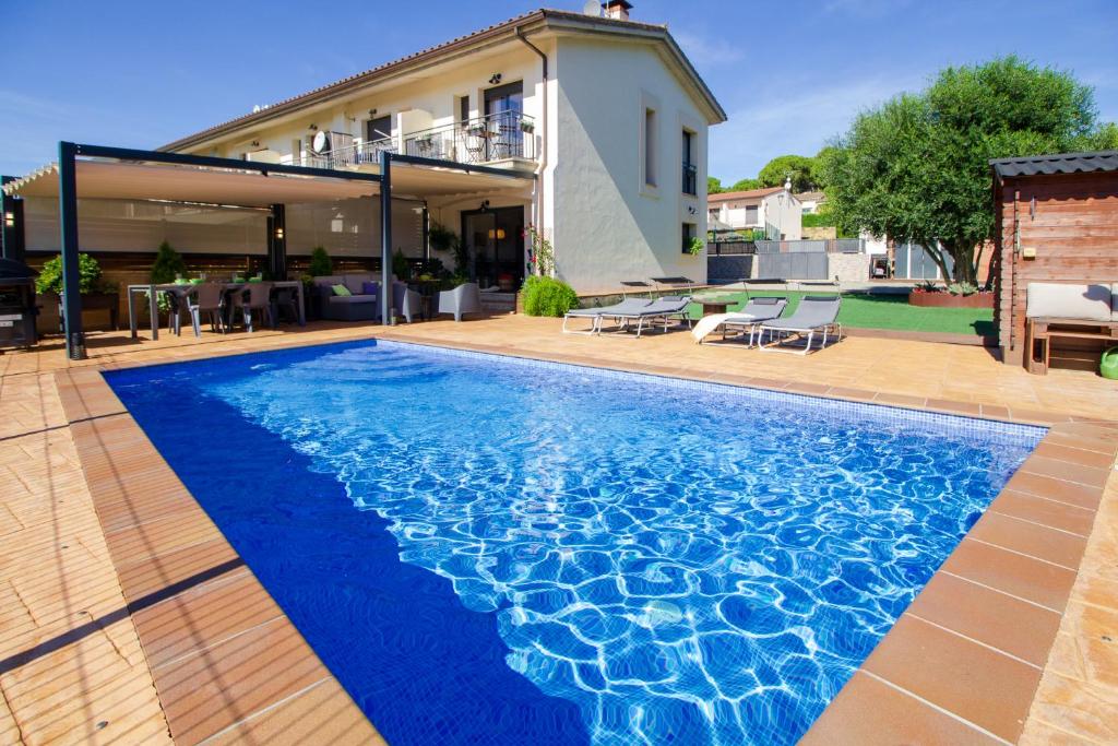 a swimming pool with blue water in front of a house at Casa Falset in L'Estartit