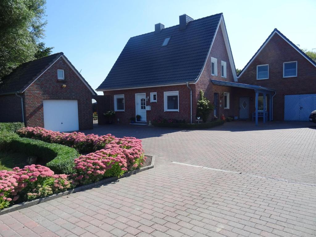 a house with a brick driveway and pink flowers at Am-Deichtor in Dornumersiel