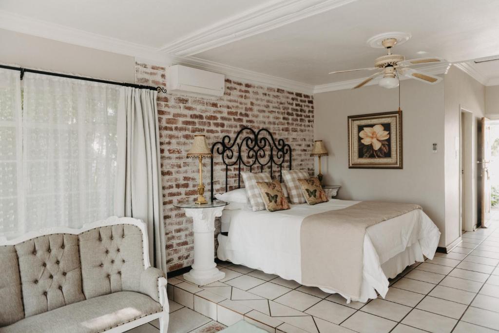 a bedroom with a bed and a chair and a brick wall at Arcadia Luxury Guesthouse in Kroonstad