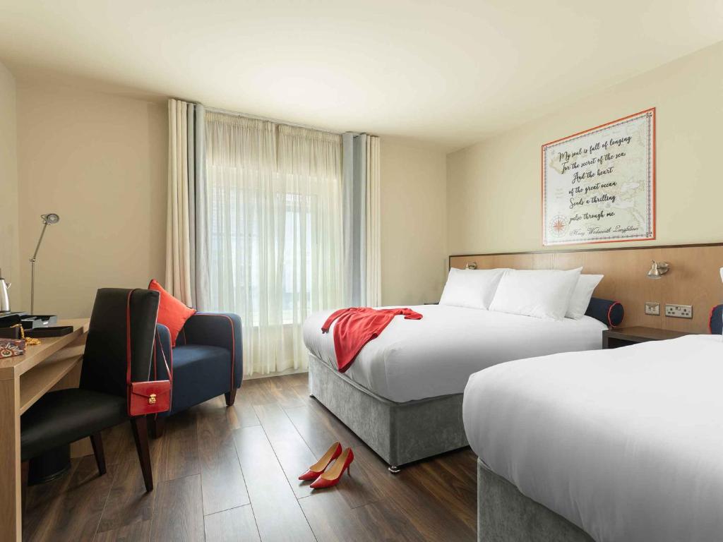 um quarto de hotel com duas camas, uma secretária e uma cadeira em The Mariner, Westport em Westport