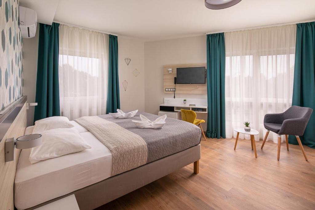 1 dormitorio con 1 cama grande y cortinas verdes en Kristály Hotel, en Keszthely