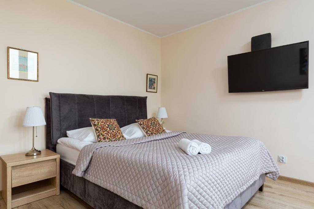 1 dormitorio con 1 cama y TV en la pared en Royal Park Apartments Warsaw Sielecka by Renters, en Varsovia