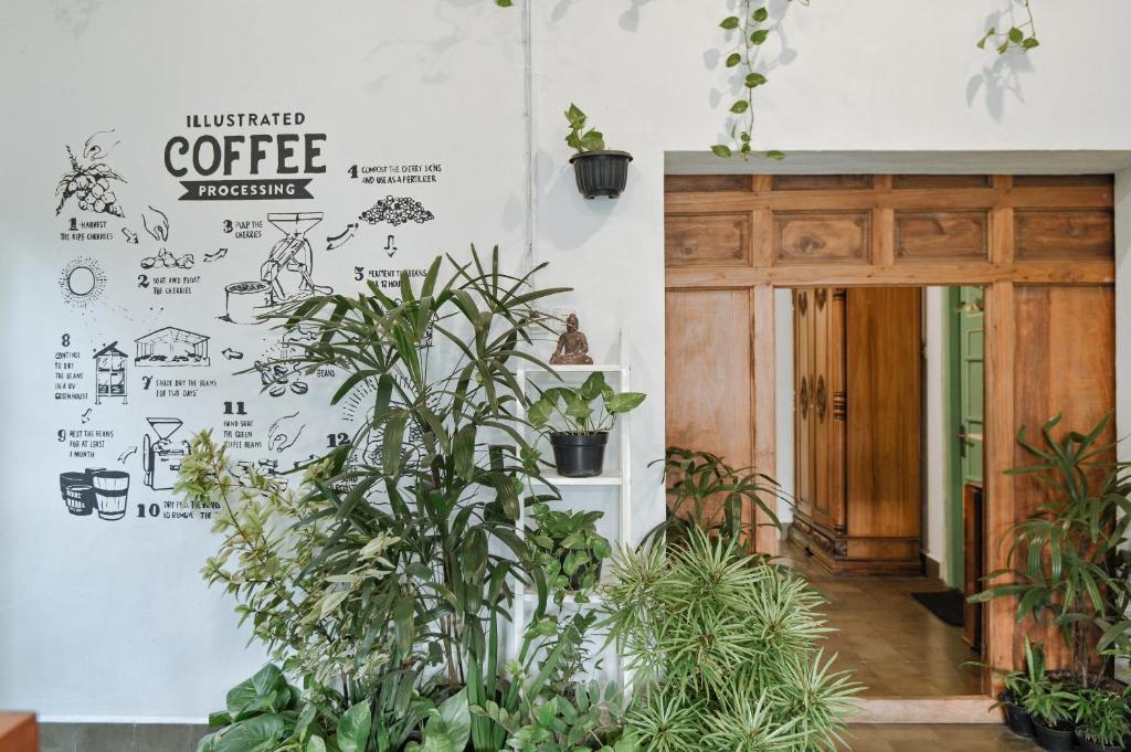 a room with plants and a wall with a coffee sign at Snooze in Yogyakarta