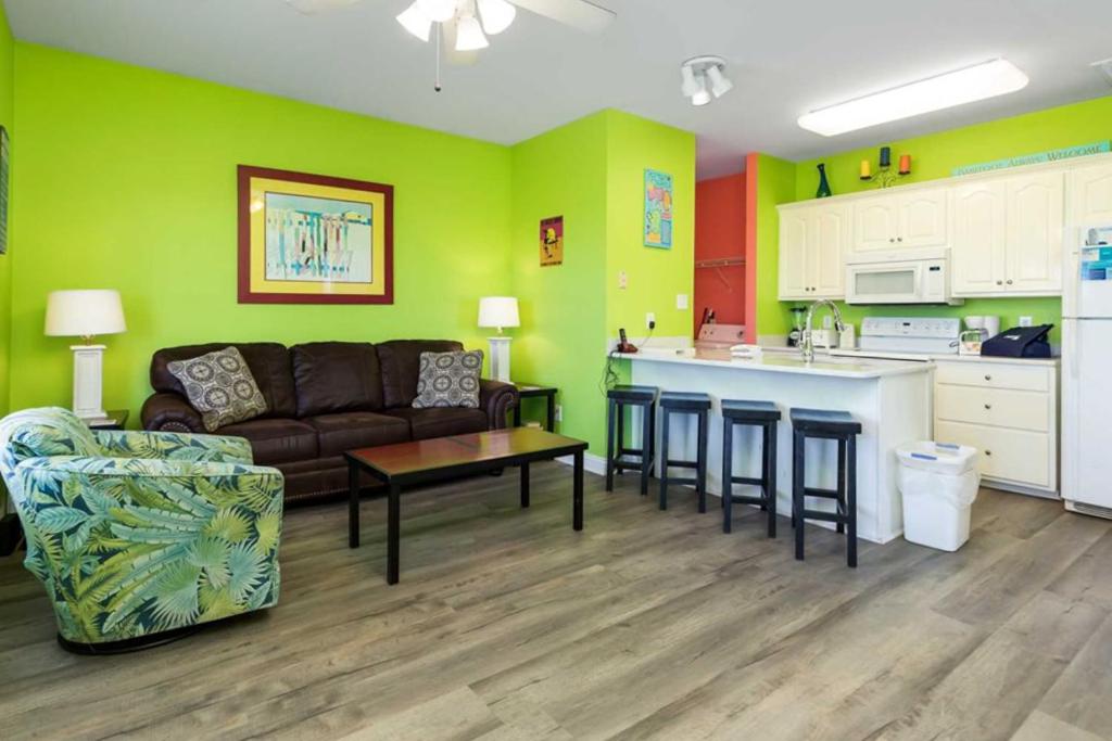 a living room with a couch and a kitchen at Plum Cute by Meyer Vacation Rentals in Gulf Shores