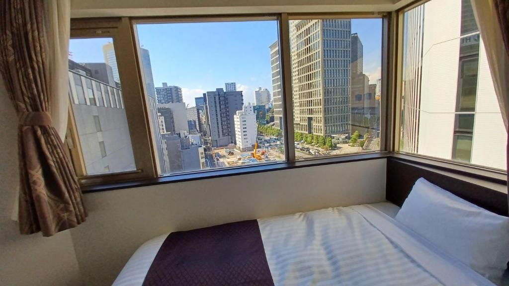a bedroom with a view of a city from a window at Akasaka Urban Hotel Annex in Tokyo