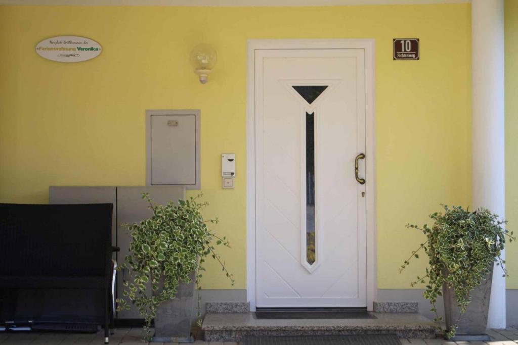 a white door on a yellow wall with two plants at Ferienwohnung Veronika in Bad Griesbach