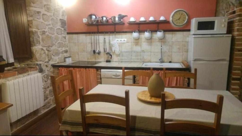 a kitchen with a table and chairs and a refrigerator at La Gesta Picos de Europa in Poo de Cabrales