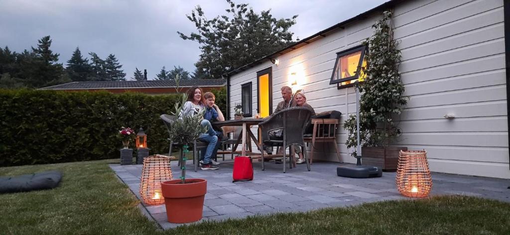 een groep mensen aan een tafel buiten een huis bij Kerkendal in Kootwijk