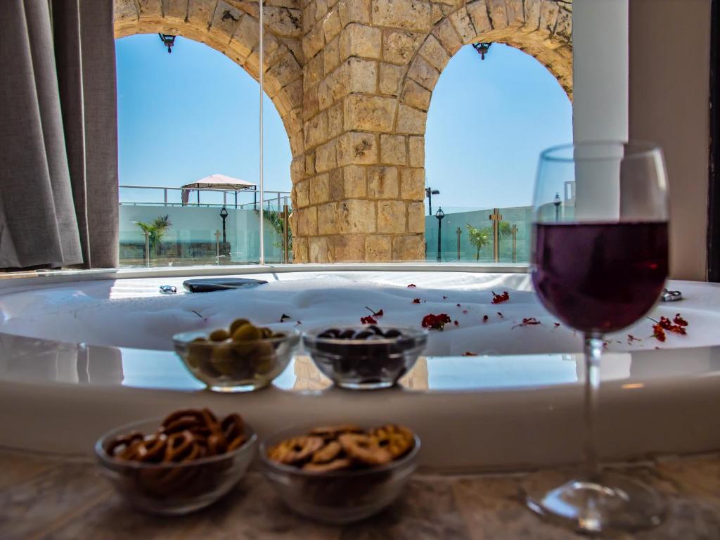 ein Glas Wein und Schüsseln mit Essen neben einer Badewanne in der Unterkunft סוויטות אושר בגולן in Had Nes