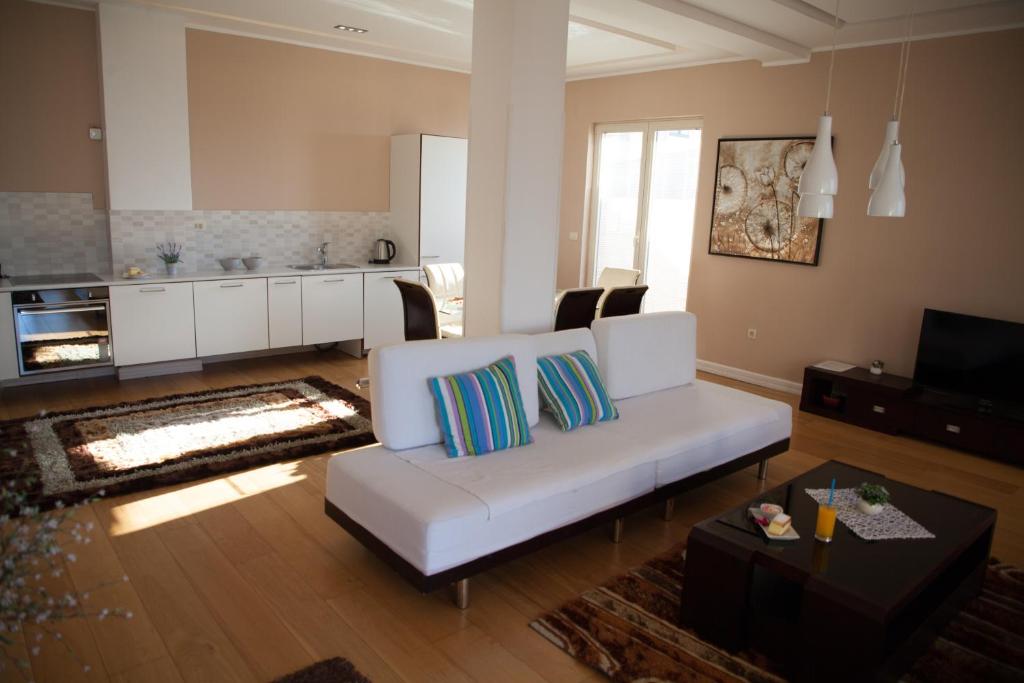 a living room with a white couch and a kitchen at Spa Resort Luxury Apartments in Budva