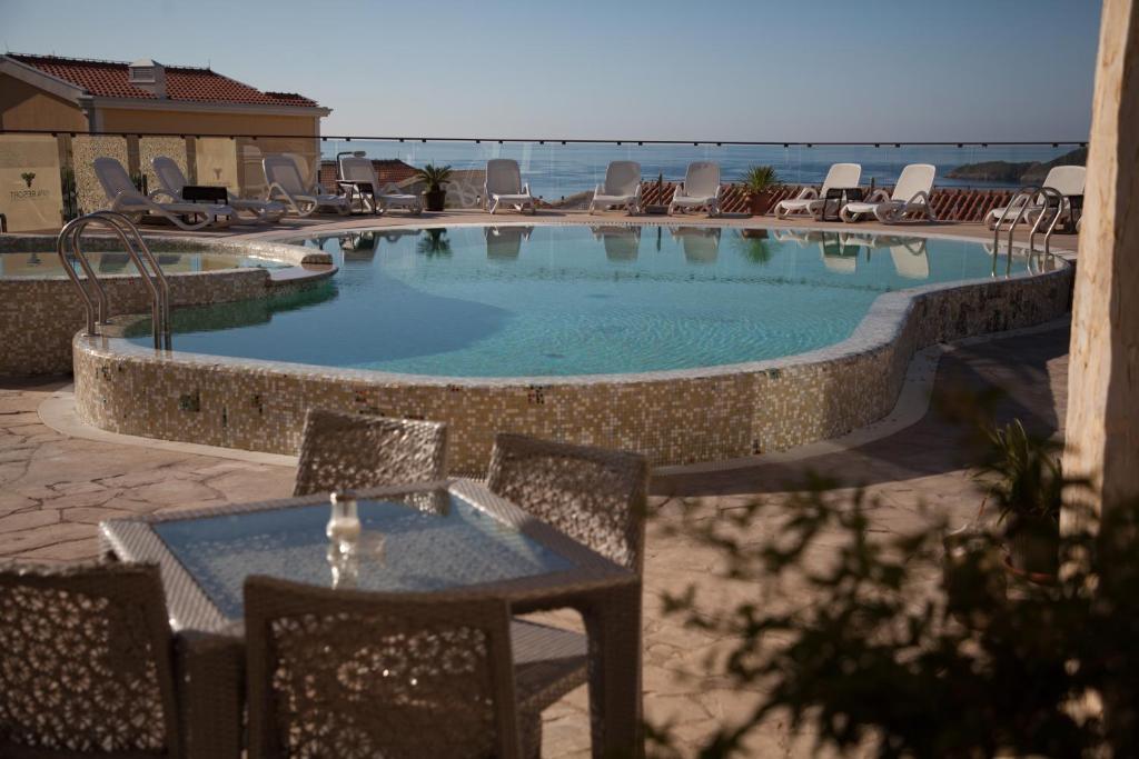 a large swimming pool with a table and chairs at Spa Resort Luxury Apartments in Budva