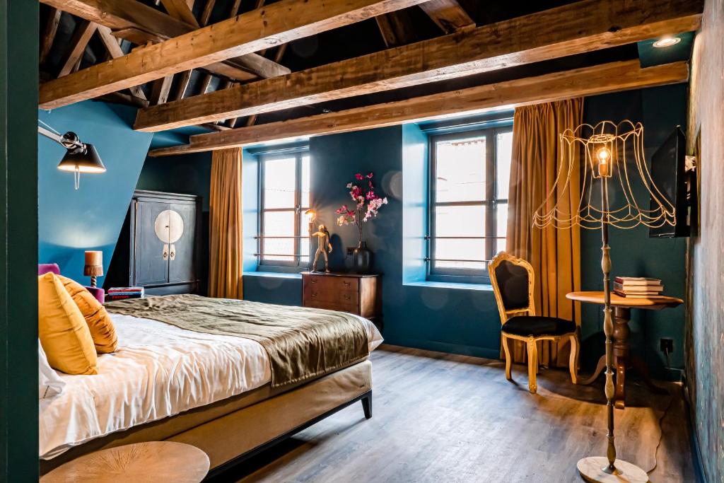 een slaapkamer met blauwe muren en een bed en een tafel bij MAF Haarlem Boutique Hotel in Haarlem