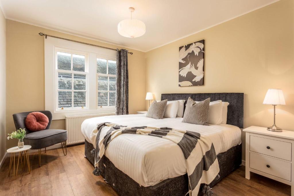 a bedroom with a large bed and a chair at The Orchard - Donnini Apartments in Ayr