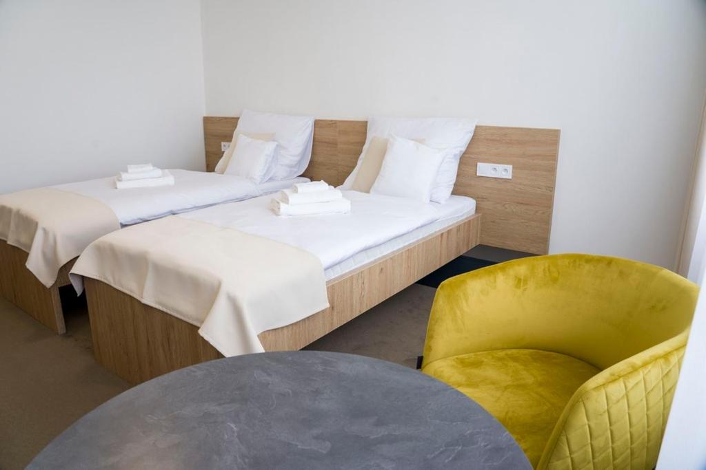 a room with two beds and a yellow chair at Wellness hotel Mestská plaváreň in Trebišov