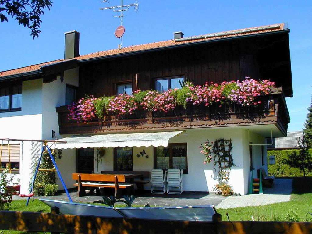 una casa con un banco y flores delante de ella en Ferienwohnungen Winkler, en Frasdorf
