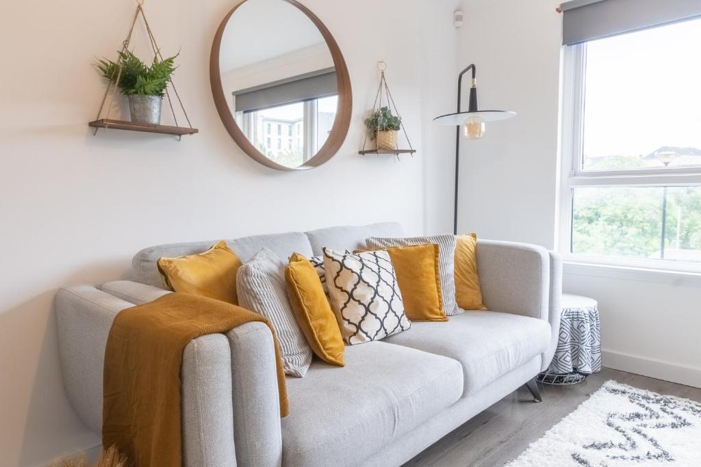 a living room with a couch with pillows and a mirror at Luxury Glasgow Flat in the heart of the Westend in Glasgow