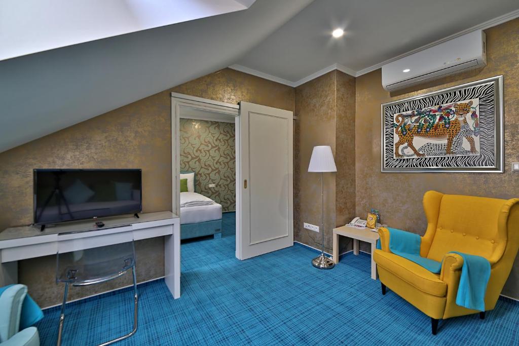 a hotel room with a television and a yellow chair at Hotel Pod Bránou in Bardejov