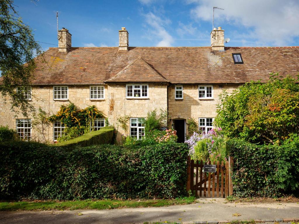 an old stone house with a gate in front of it at Swallows Rest in Broadway