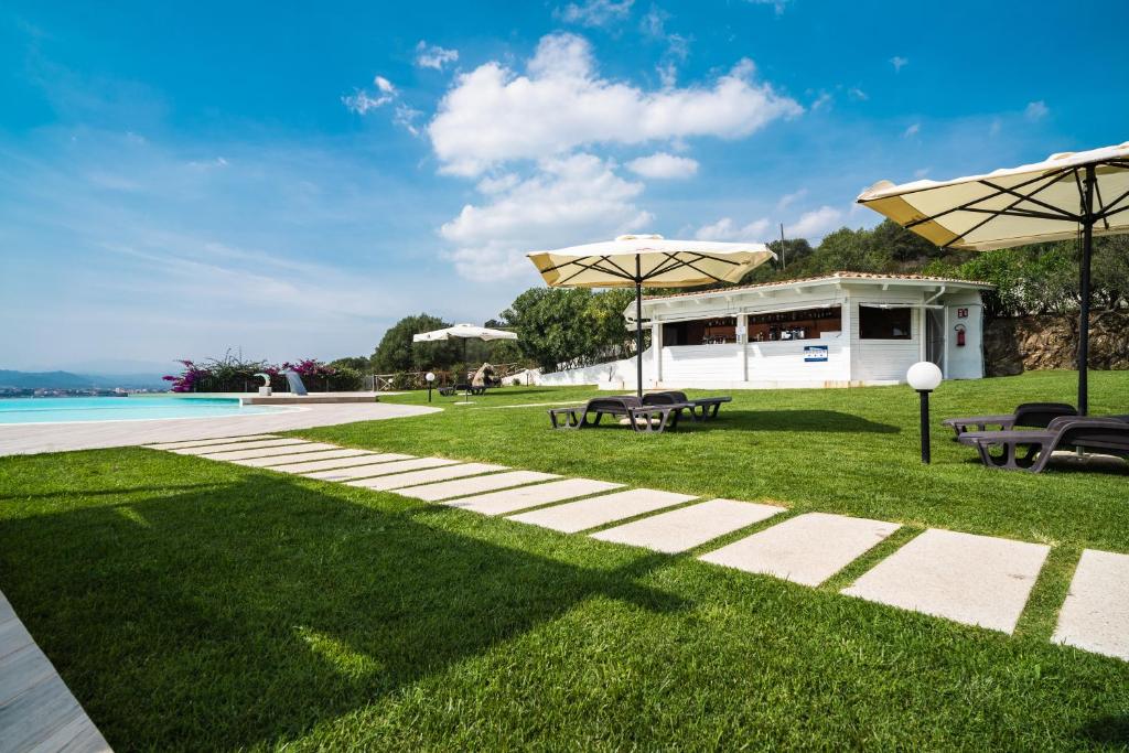 a garden with tables and umbrellas and a pool at Hotel dP Olbia - Sardinia in Olbia