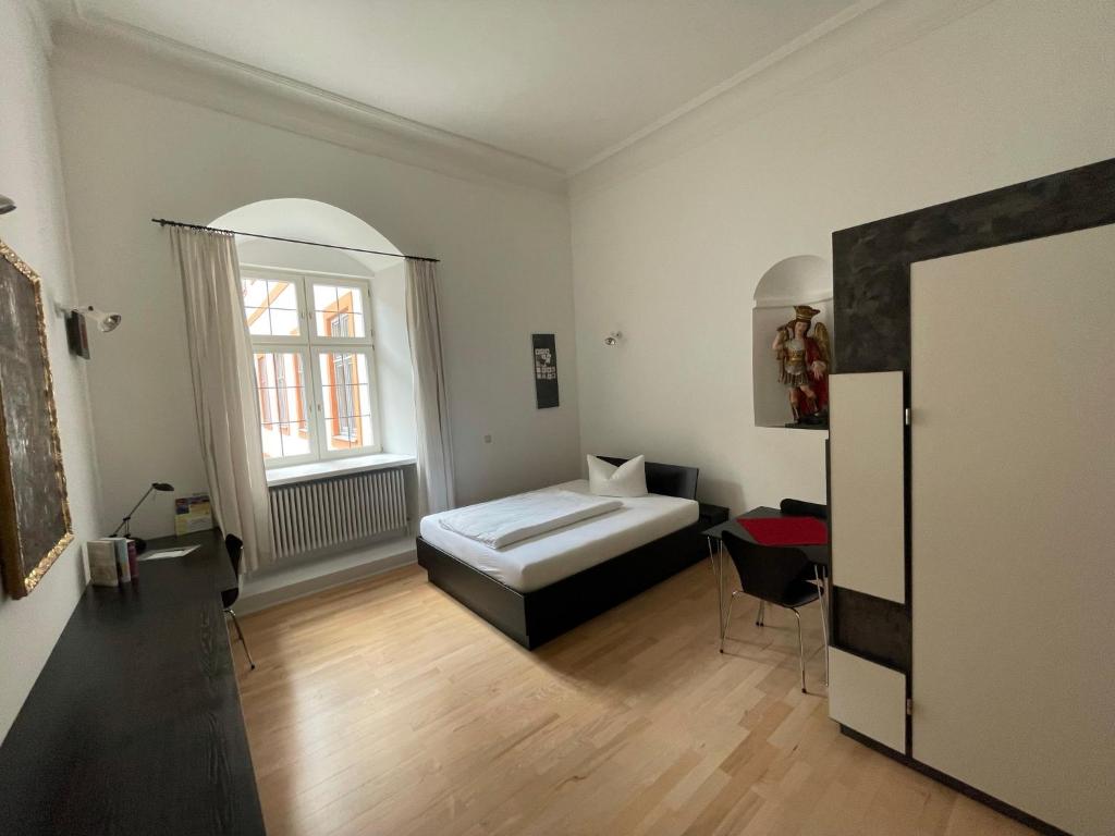 ein weißes Zimmer mit einem Bett und einem Fenster in der Unterkunft Bischöfliches Seminar St. Willibald in Eichstätt