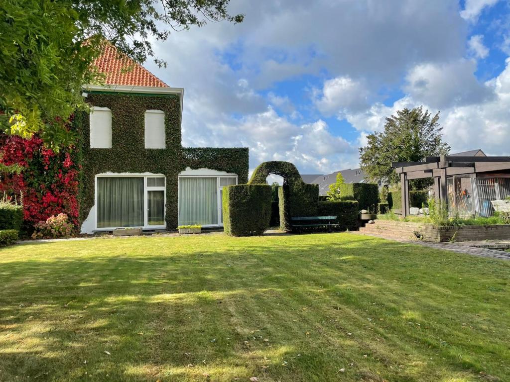 a house with a green yard with a grass field at B&B The White House in Wielsbeke