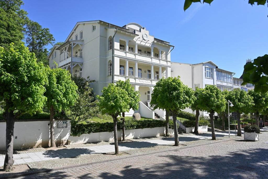 un grand bâtiment blanc avec des arbres devant lui dans l'établissement Ferienwohnung 13 Villa Celia Sellin, à Sellin
