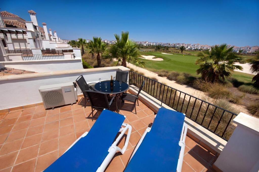 een patio met blauwe stoelen en een tafel op een balkon bij Townhouse overlooking golf course in Las Armeras