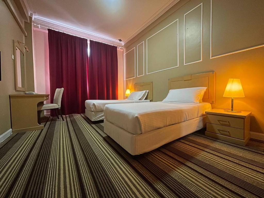 a hotel room with two beds and a red curtain at Hotel UiTM Shah Alam in Shah Alam