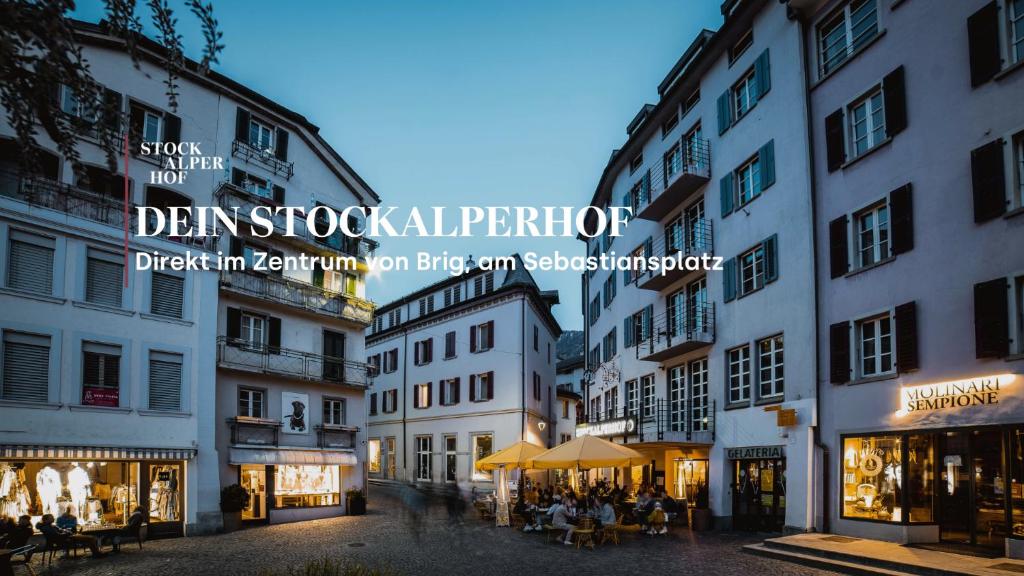 una calle de la ciudad con edificios y gente sentada en mesas en Hotel Stockalperhof, en Brig