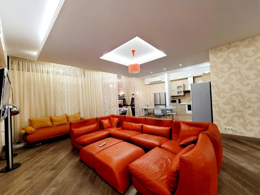 Arcadia Apartments في أوديسا: غرفة معيشة مع أريكة برتقالية ومطبخ