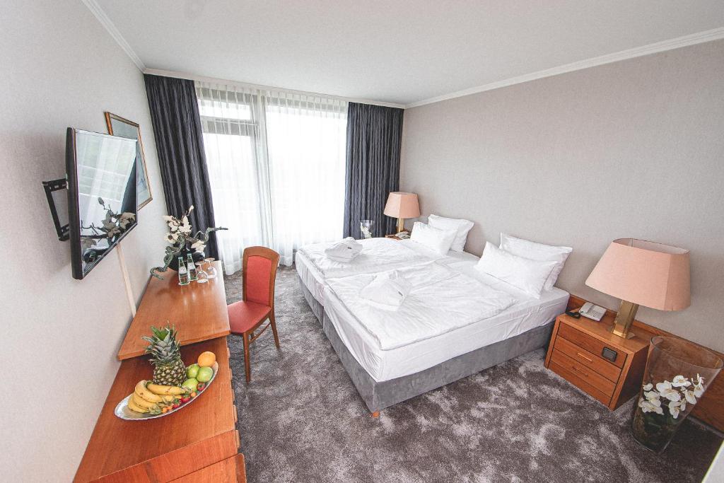 Cette chambre comprend un lit et une table avec un bol de fruits. dans l'établissement PLAZA Hotel Gelsenkirchen, à Gelsenkirchen