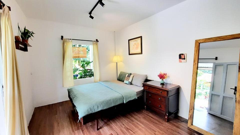 Schlafzimmer mit einem Bett, einer Kommode und einem Spiegel in der Unterkunft Vườn Nhà Ngoại Garden Homestay in Cu Chi