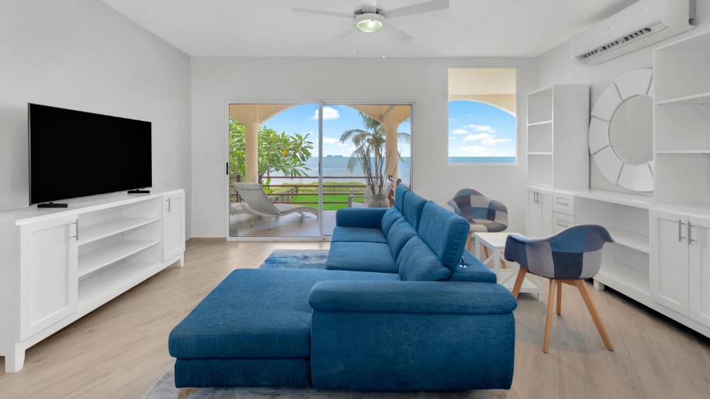 a living room with a blue couch and a tv at 3-Bedroom, 2-Bath Beachfront Condo with Pool in Playa Flamingo