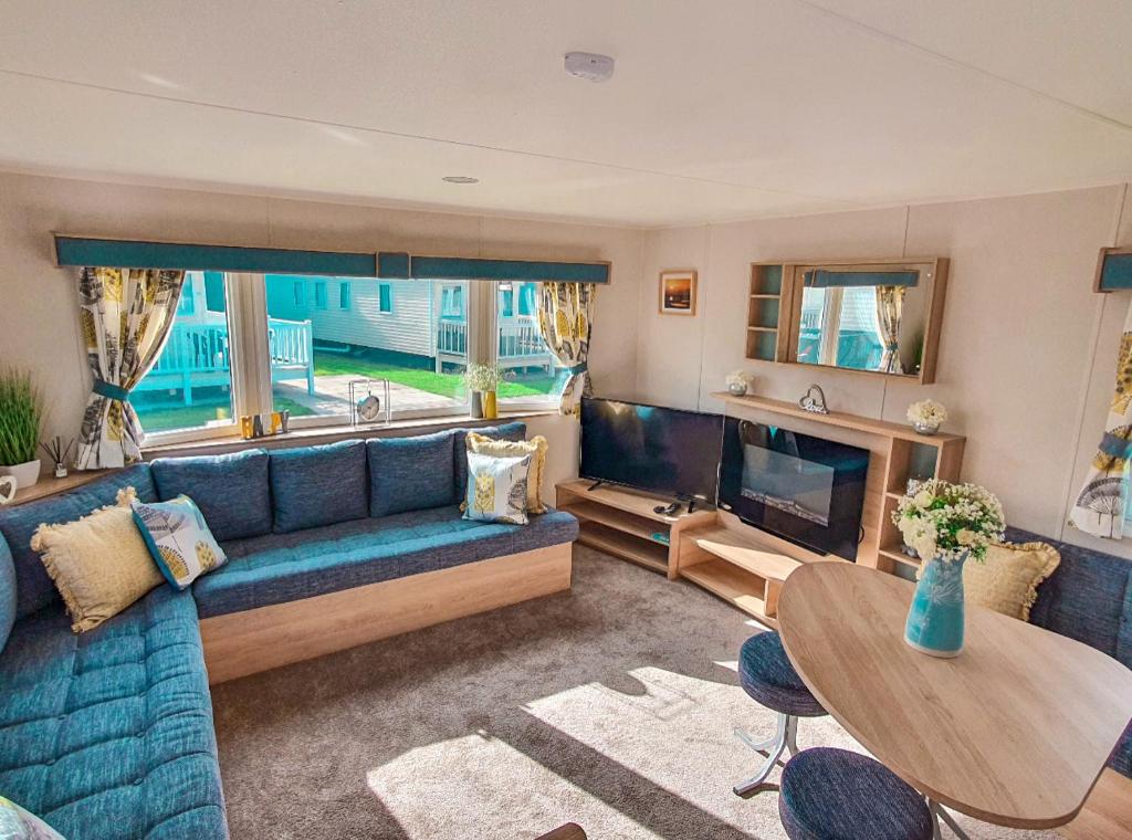 a living room with a blue couch and a television at Spacious Caravan - Thorpe Park Cleethorpes in Humberston