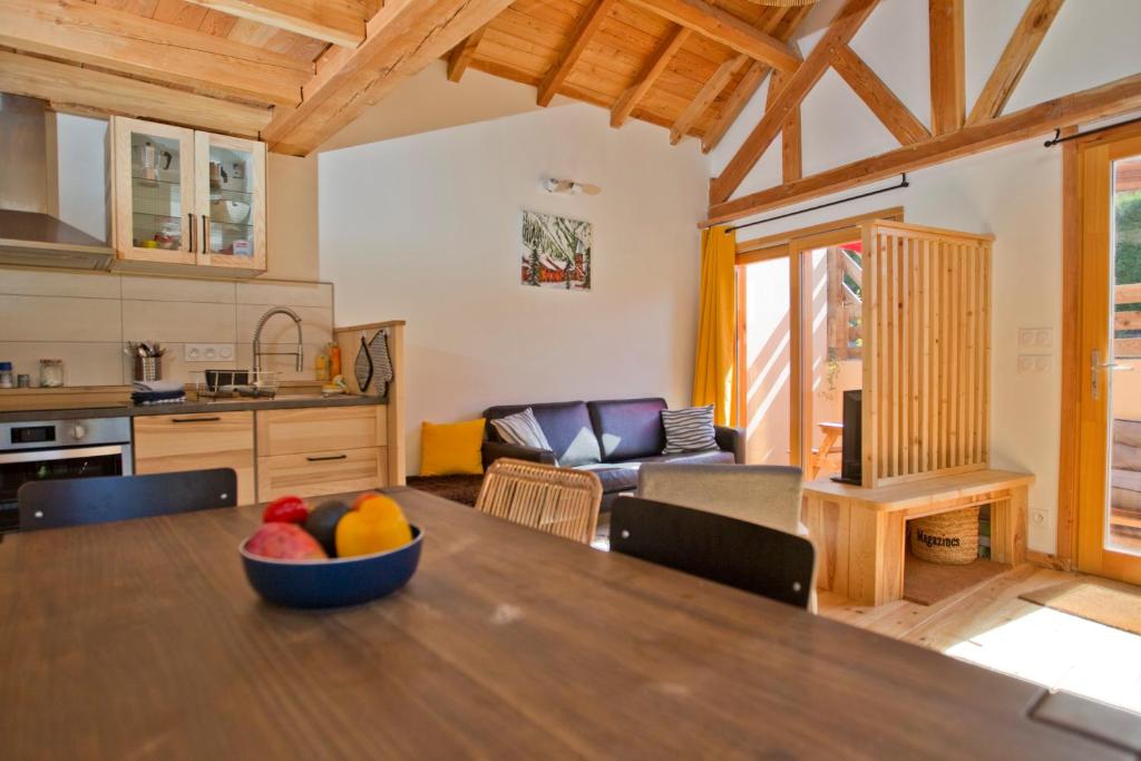 a kitchen and living room with a bowl of fruit on a table at Petit Chalet Montagne in Briançon