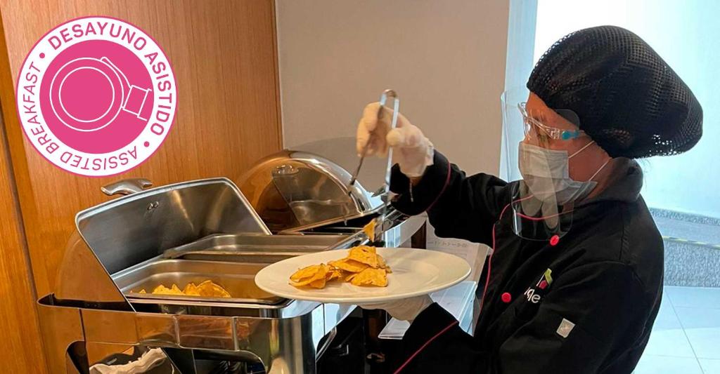 a person wearing a mask holding a plate of food at Hotel MX roma in Mexico City