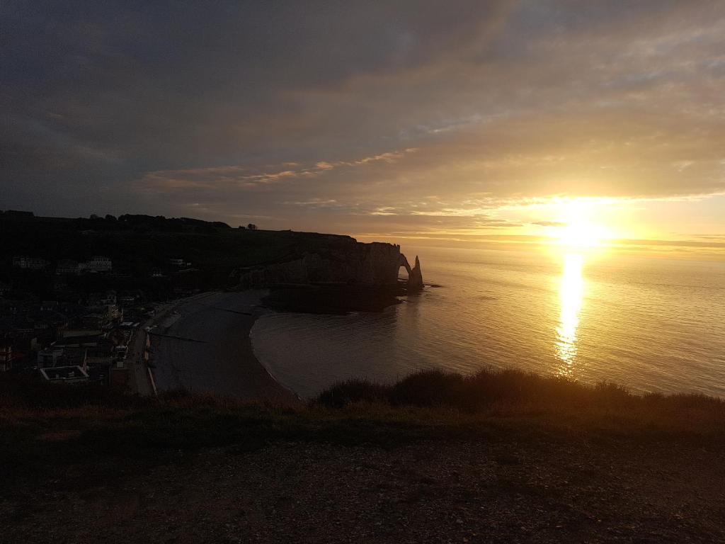 a sunset over a body of water with the sun setting at LES LUPINS in Étretat