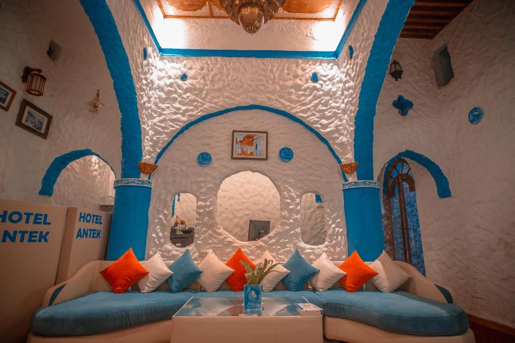 a room with a blue couch with colorful pillows at Riad Antek in Chefchaouene