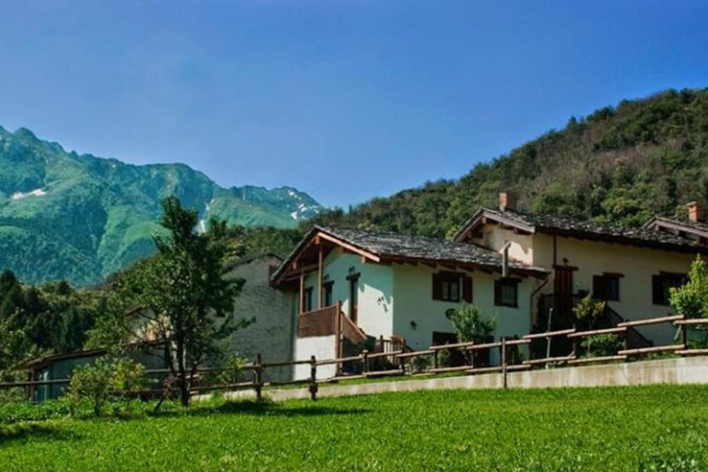 a house in a field with mountains in the background at B&B Alla Borgata in Boves