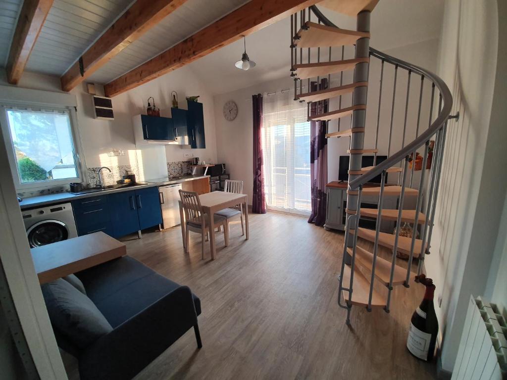 a living room with a spiral staircase and a kitchen at Nuits & Jours Duplex à Nuits Saint Georges in Nuits-Saint-Georges