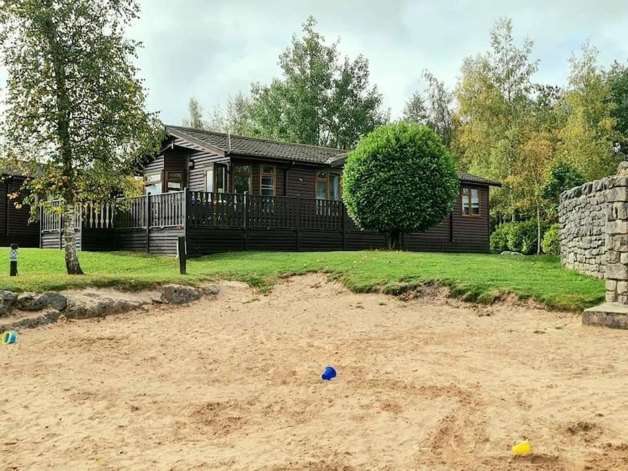 une maison avec un bac à sable devant une cour dans l'établissement 4 Bed Luxury Lodge with Hot tub near Lake District, à Warton