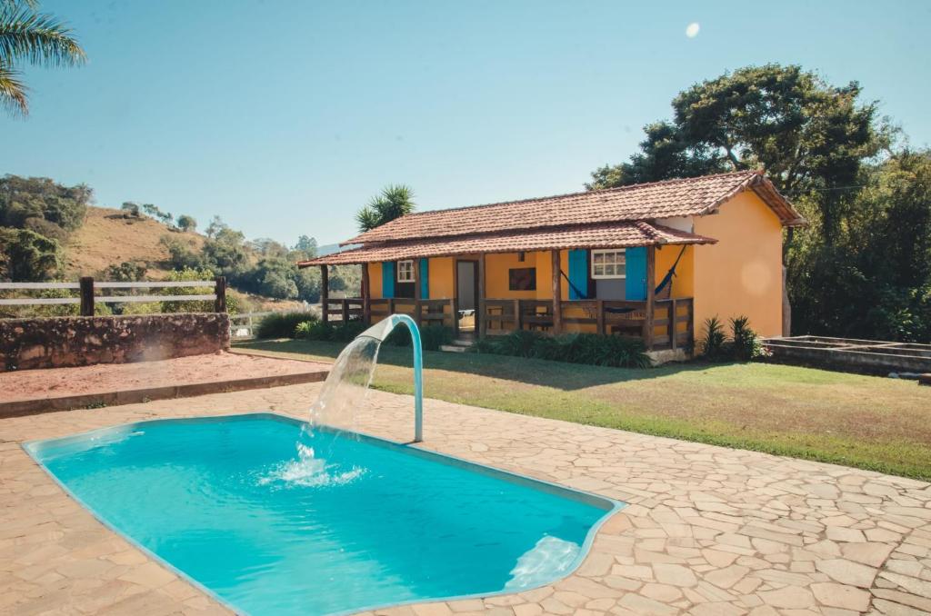 a swimming pool with a fountain in front of a house at Fazenda do Engenho in Ritápolis