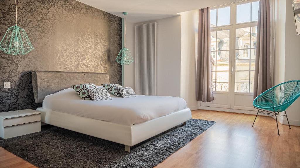 a bedroom with a white bed and a blue chair at LA CASA DEL GUSTO in Loudun