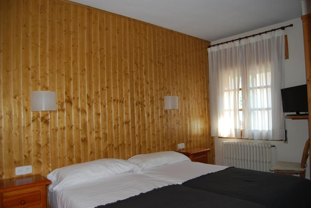 a bedroom with a bed and a wooden wall at Pension Casa Vicenta in Vielha
