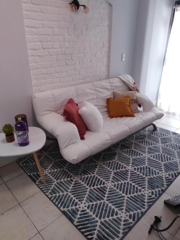 un sofá blanco con almohadas sobre una alfombra en la sala de estar en Pocitos Nuevo, en Montevideo