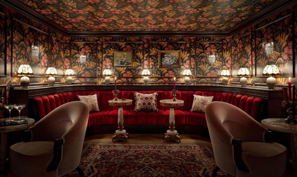 a red booth in a room with a wall covered in wallpaper at The Randolph Hotel Oxford, a Graduate by Hilton Hotel in Oxford